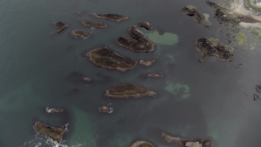 The rocks are all along the shore in the water