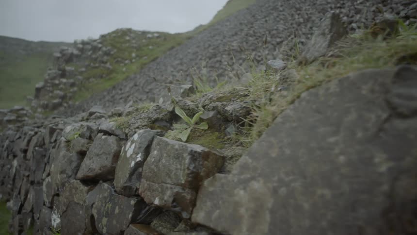 A cliffside that has rocks stacked against it in a wall