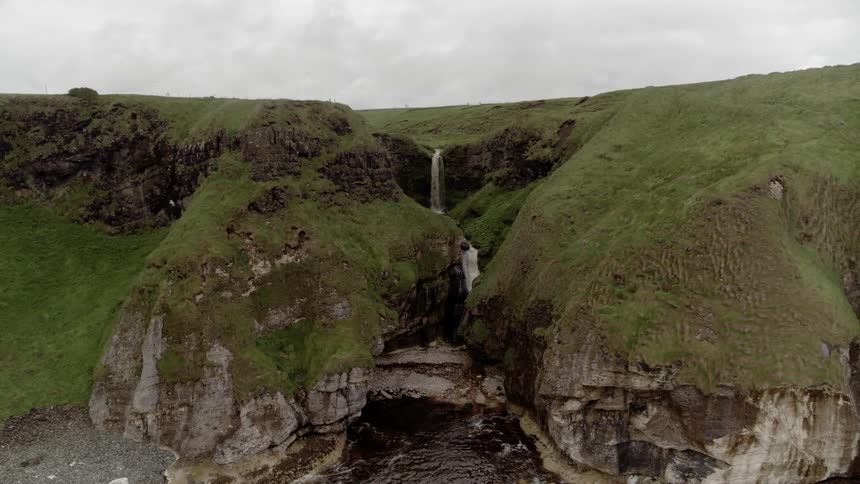 A water fall streams down into a larger body of water