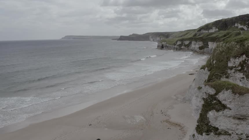 A man is standing by the cliff near the shore