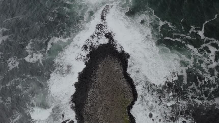 An aerial view of ocean waves flowing towards the shoreline