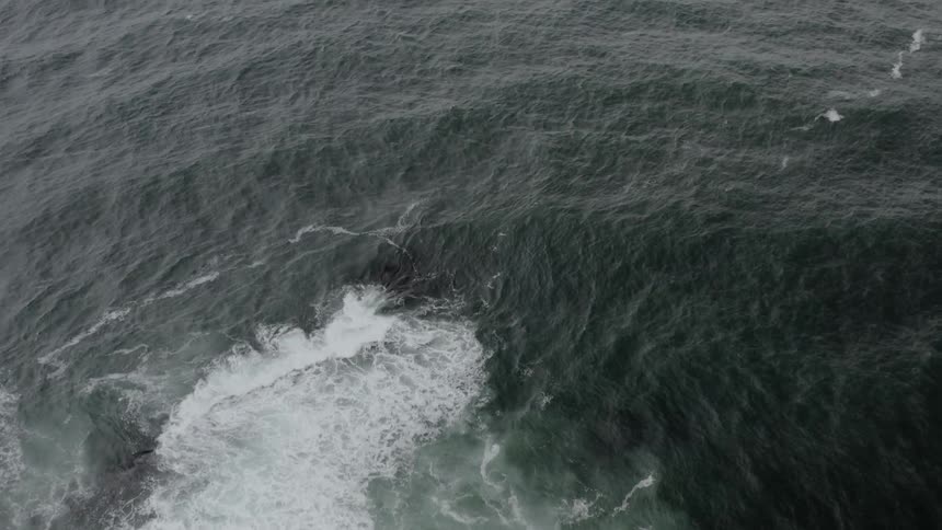 Aerial shot of a cliffside into the ocean