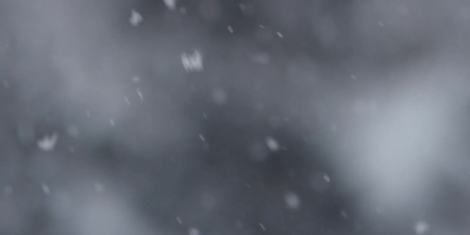 Snowfall with lights in the background