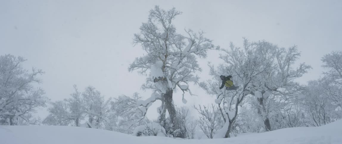 Snow falls as a skier jumps through the air