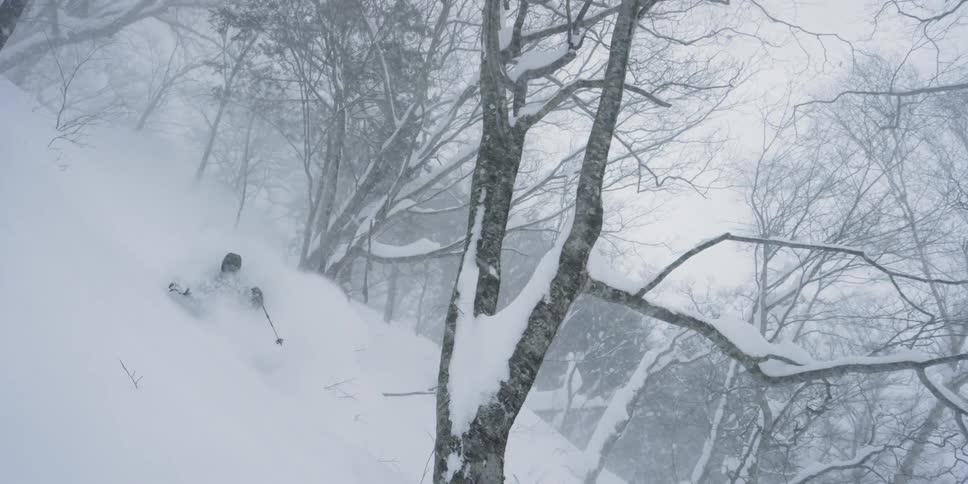 A skier glides down a snowy mountainside during a winter storm