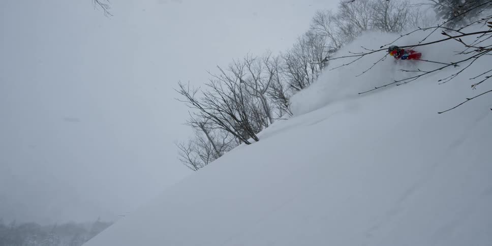 A person skiing down a snow covered slope surrounded by hills