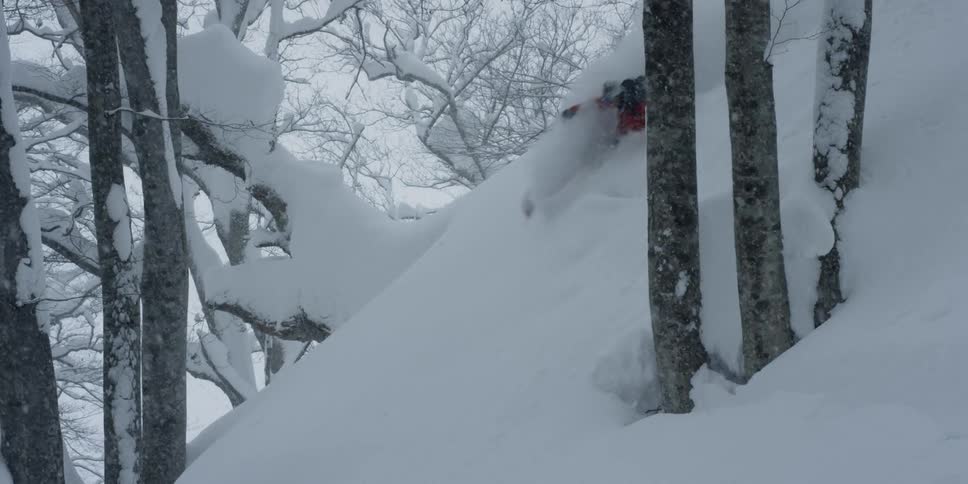 A skier glides down a steep mountainside during a winter storm