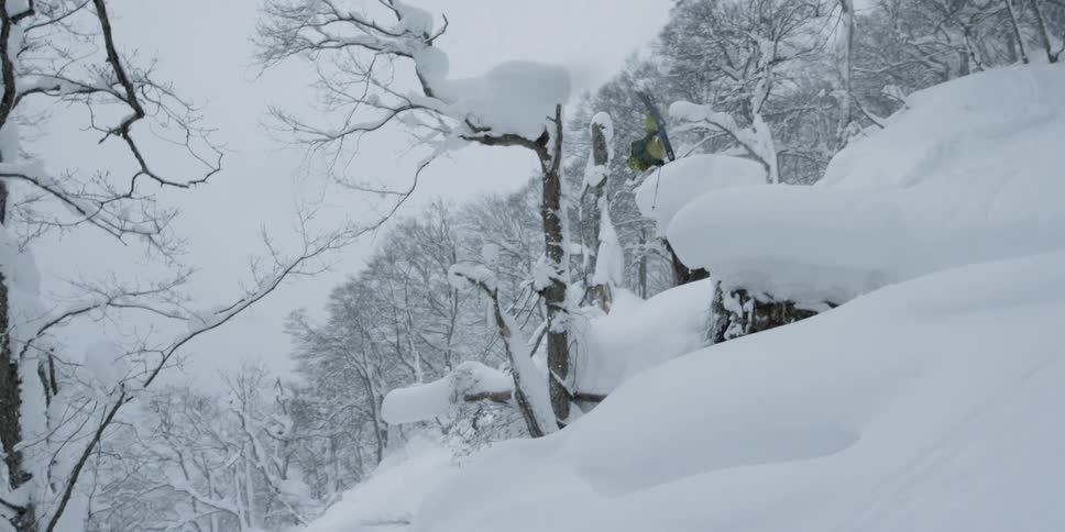 A person skiing down a snowy slope jumping and flipping