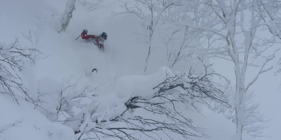 A skier glides through deep snow on a mountainside