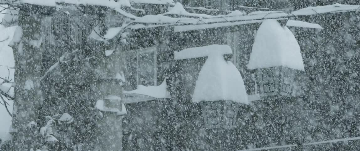 Snow falls heavily and piles high on outdoor lamps