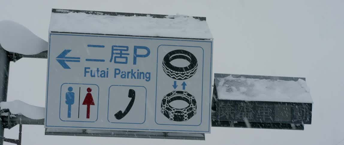 A street sign being covered in snow on a snowy winter day