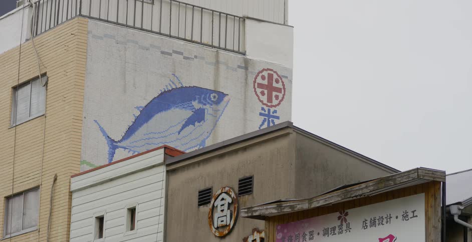 A fish mural covers the wall of a brick building
