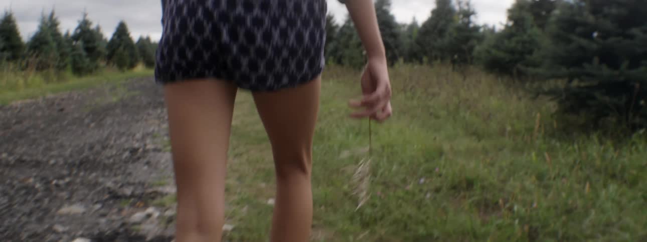 A woman leaves a path and walks into a grassy area