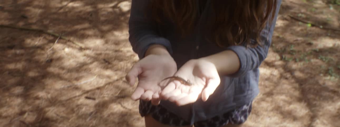 A woman holds a lizard in her hands