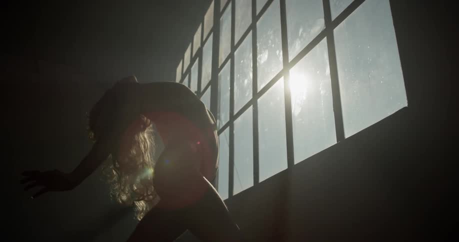 A female blonde caucasian female dancing in a dark room
