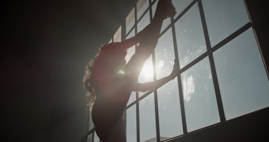 A woman next to a window stretching her legs
