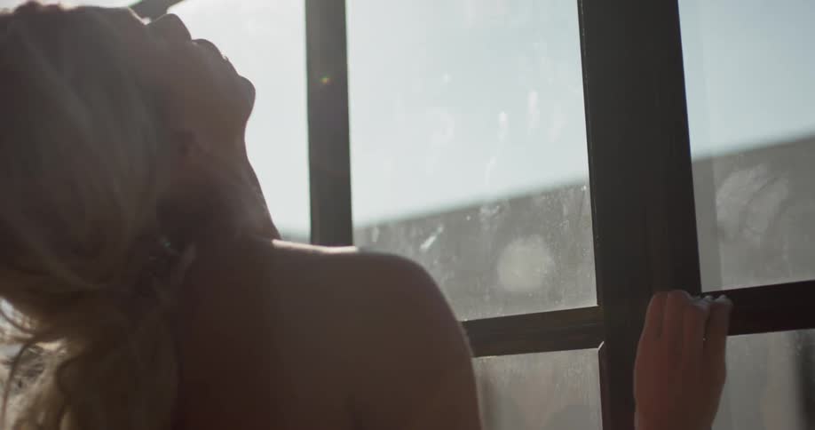 A female dancer with long blonde hair rehearses next to a window