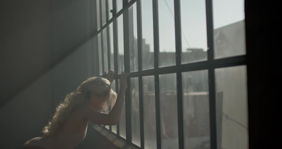 A woman in a bodysuit stretches against a georgian window letting in the morning sun