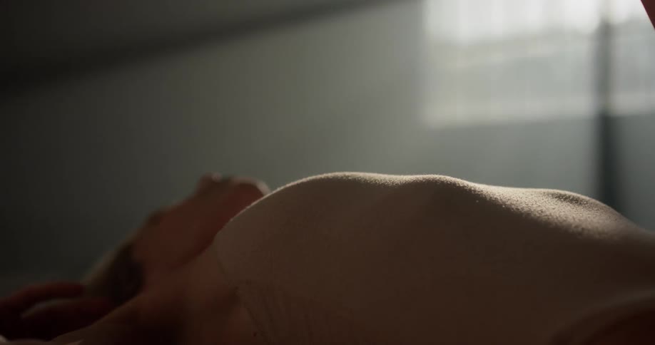 A female dancer in a pink leotard lies down in a sunny dance studio