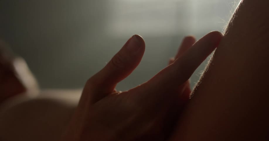 A white woman rubs her fingers down her leg while she lies on the floor