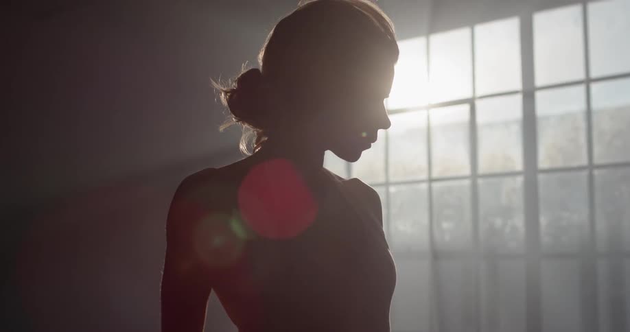 Hidden in a silhouette a woman is slowly revealed by the sun casting through the windows