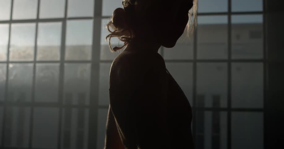 Woman stands looking out a large window