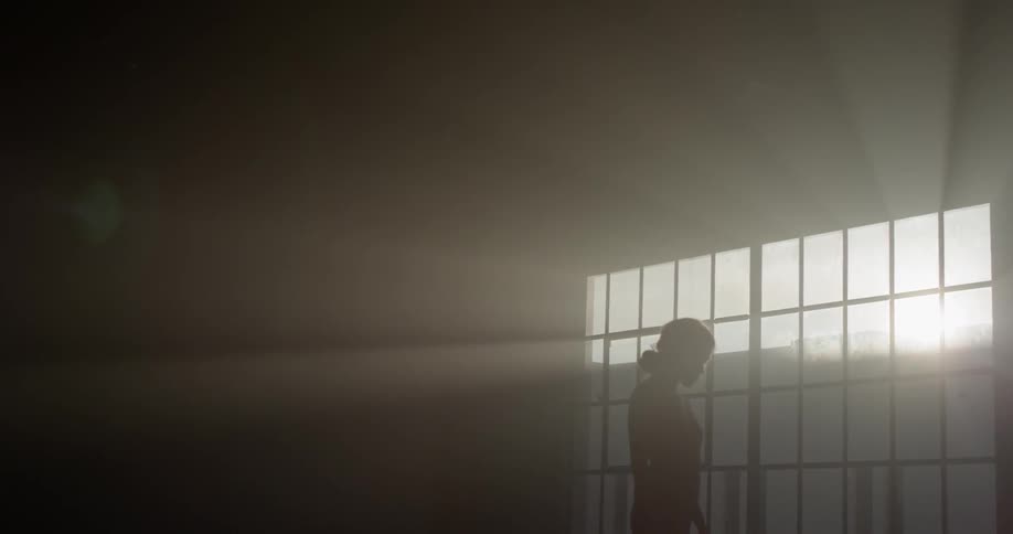 The silhouette of a woman standing in a dance pose in front of a window