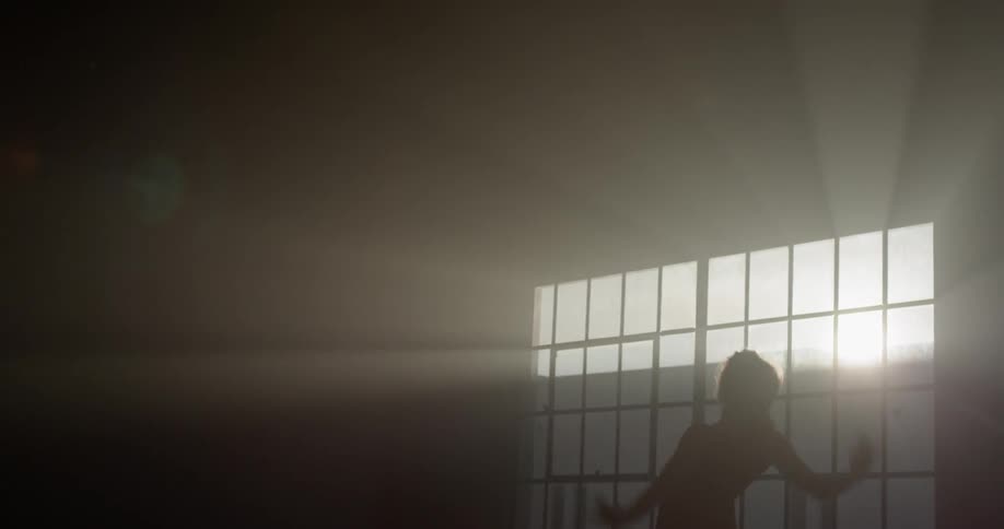 A woman dances in the sunlight through the window