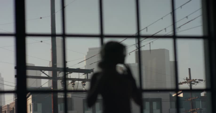 A woman in a bodysuit performs dance poses in front of a georgian window letting in the morning sun