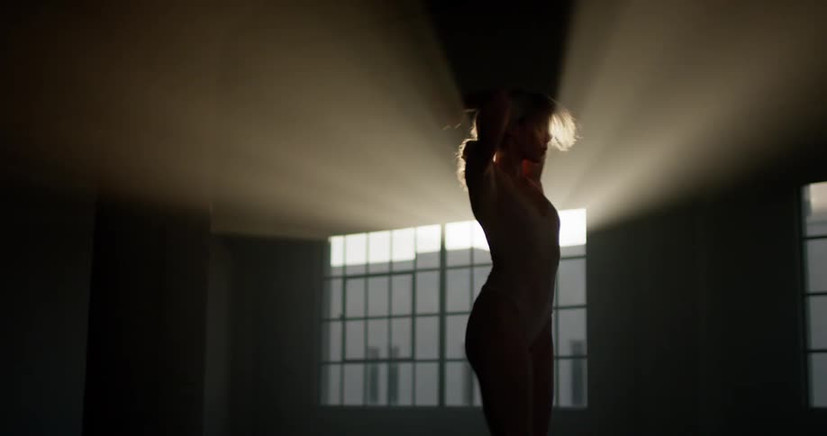 A woman in a bodysuit does a pirouette in front of a georgian window