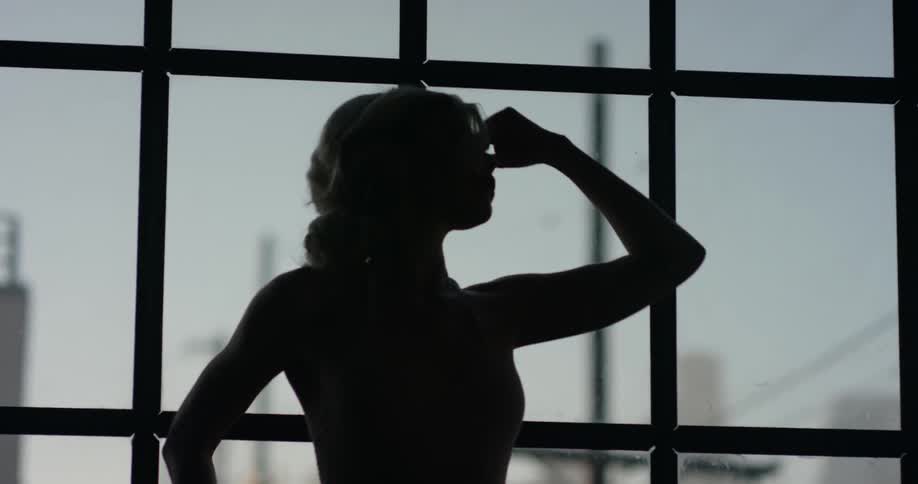 A woman in front of a window doing dance poses