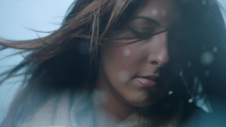 Wind blows the hair of a woman in a white scarf