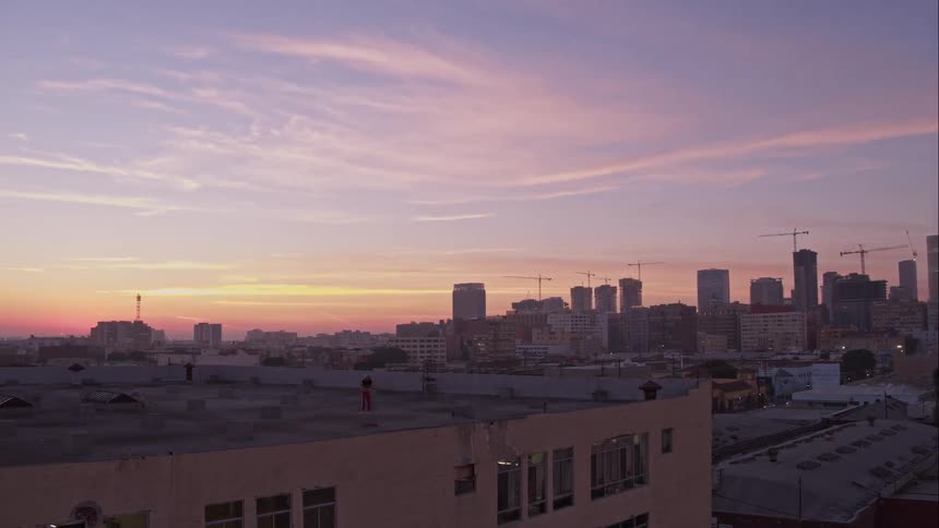 A city skyline with a man dancing on a rooftop