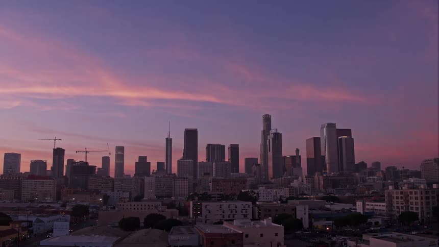 A colorful sky and clouds sit above a large city