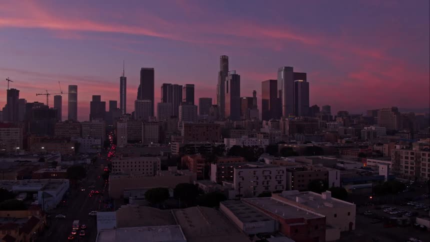 A city skyline at dawn with traffic on the roads