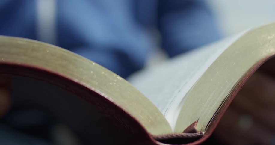A person turns a page of a book in daylight