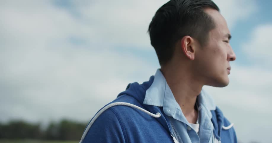 A young asian man looks in to the distance