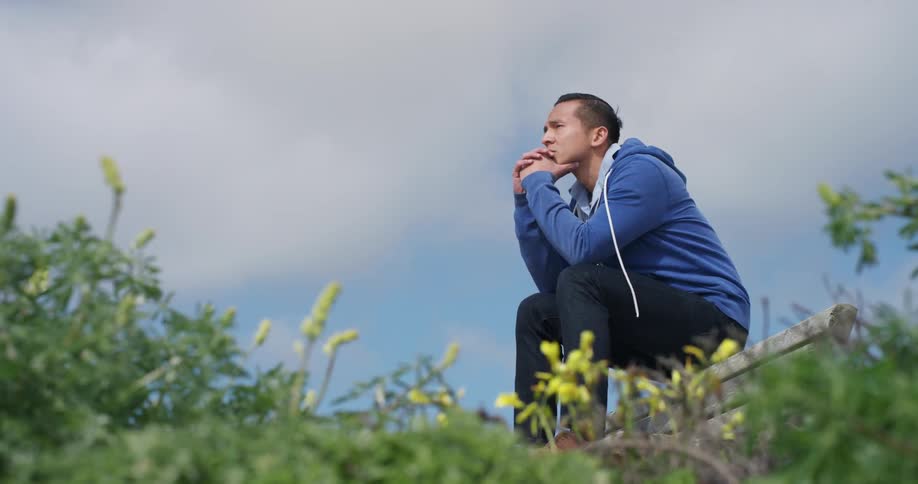 A man is sitting on a bench on a windy day