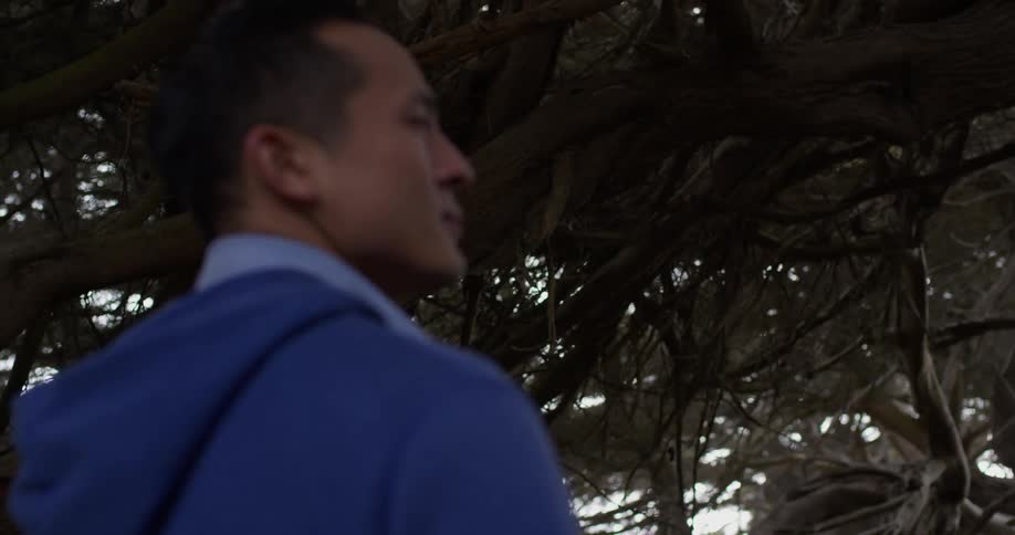 An asian man in a blue shirt looking around