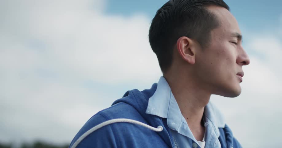 A young asian man looks out in to the distance