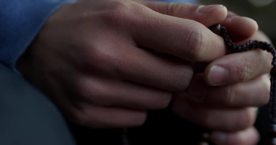 A seated man is fiddling with beads on a string