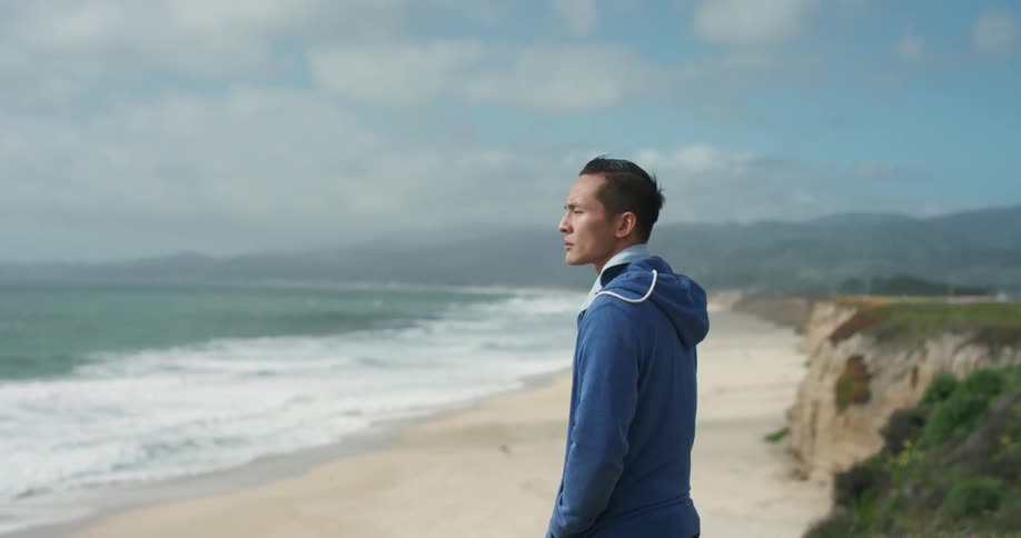 A man stands on the beach and stares at the ocean