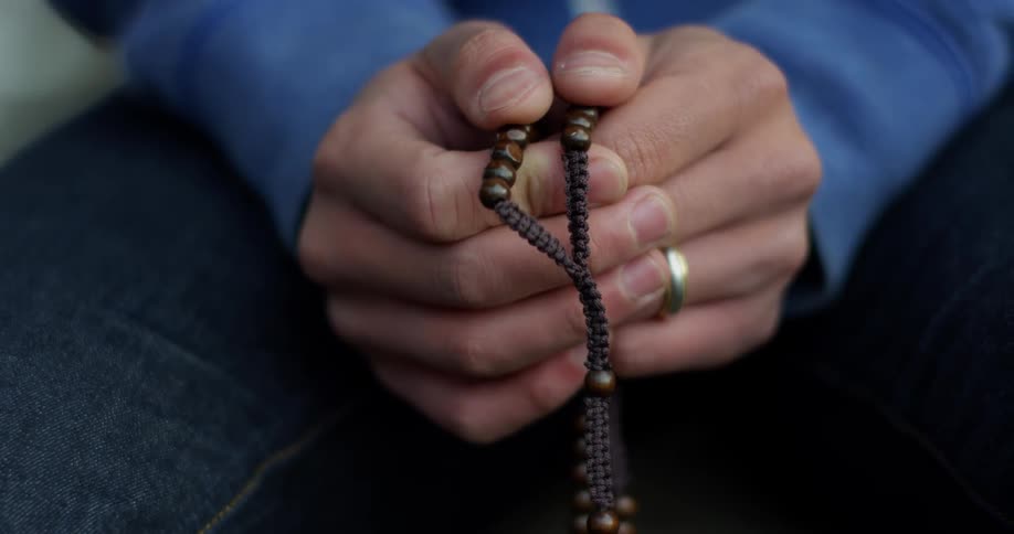 A young man holds a rope with beads in his hands