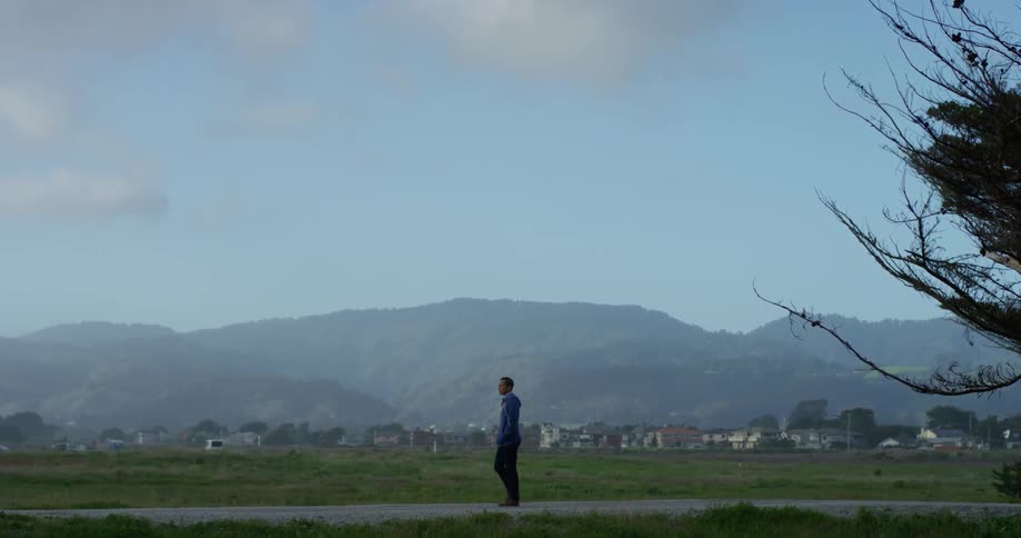 A young man walks along a sidewalk