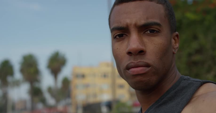 A man stands outside in a neighborhood and glares
