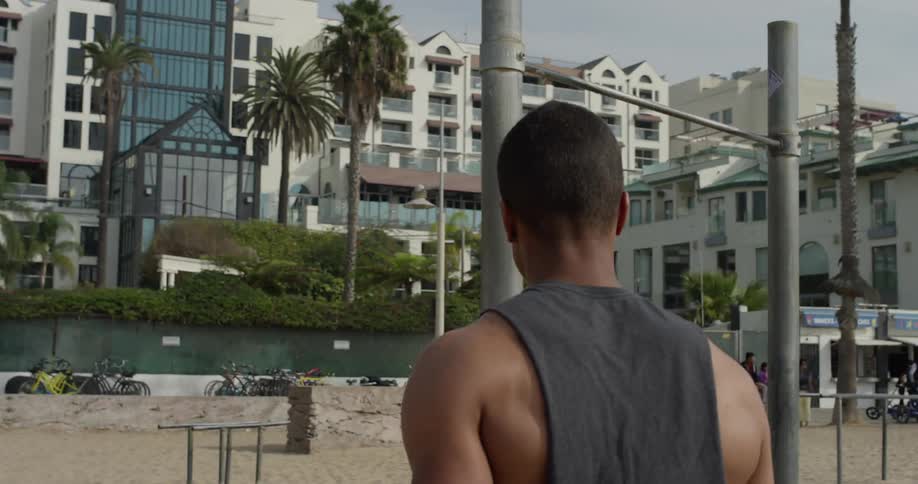 A man walks between workout equipment on a beach