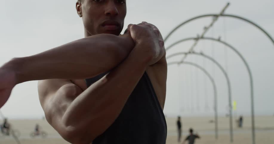 A black man stretches on the beach