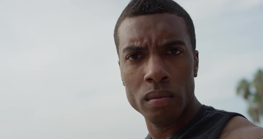 A close up of a man standing near the beach zooms out and fades away