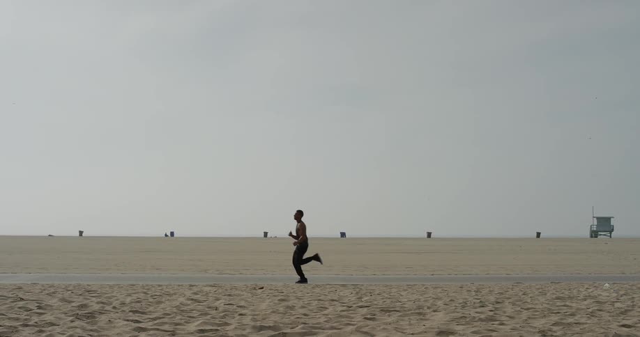 A man runs on a trail through an empty beach