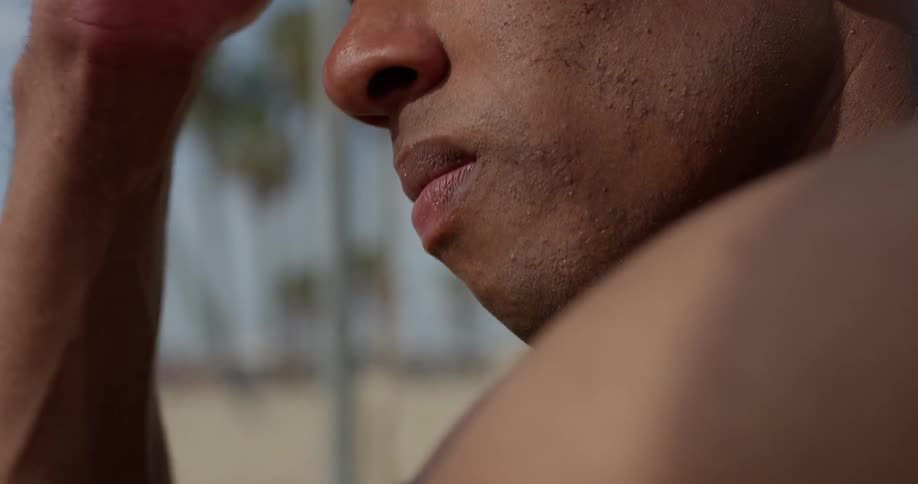 A man is sitting by the beach and puts his hand to his forehead in frustration